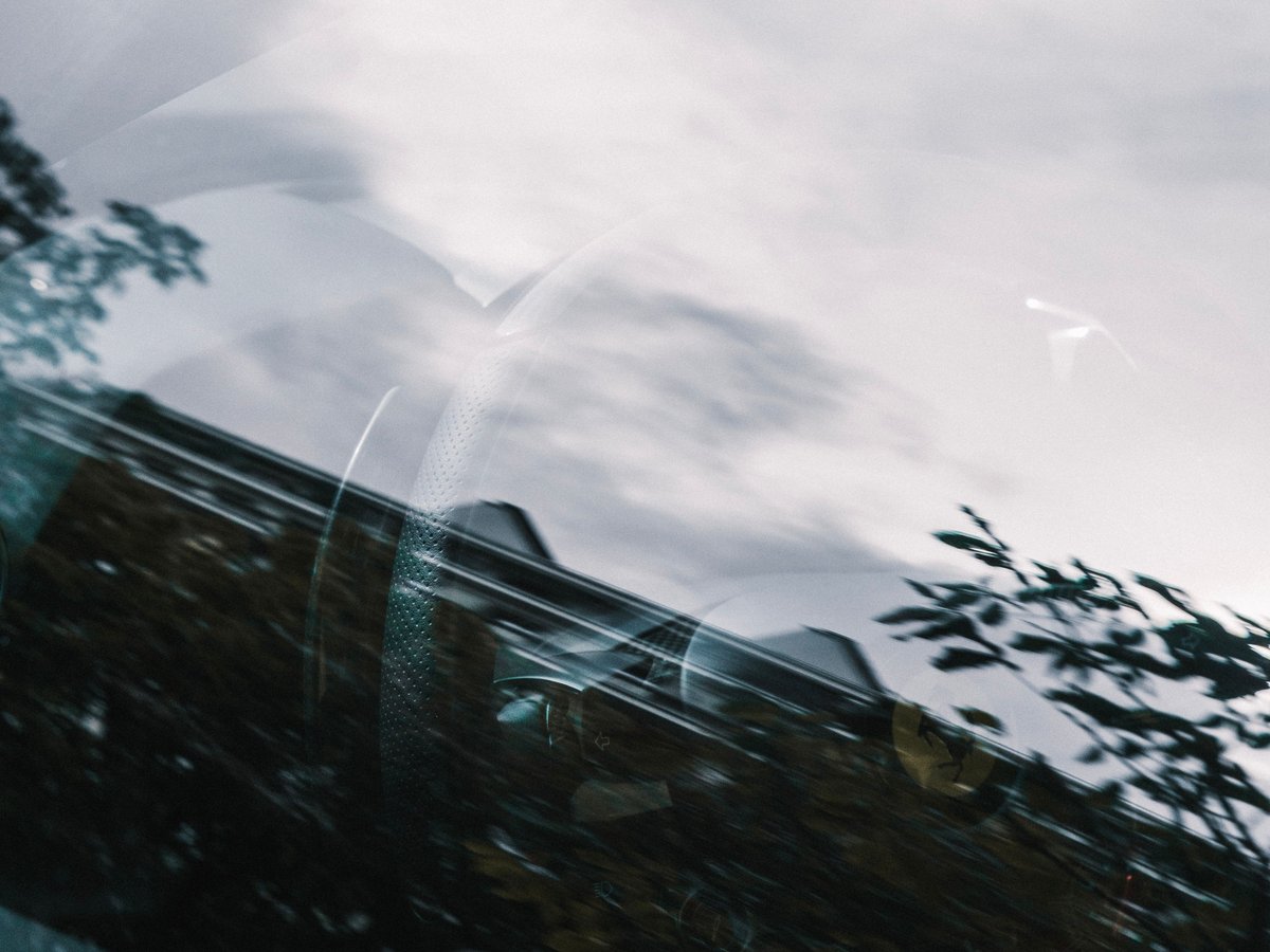Detalhe de janela de automóvel com reflexos do céu e de árvores